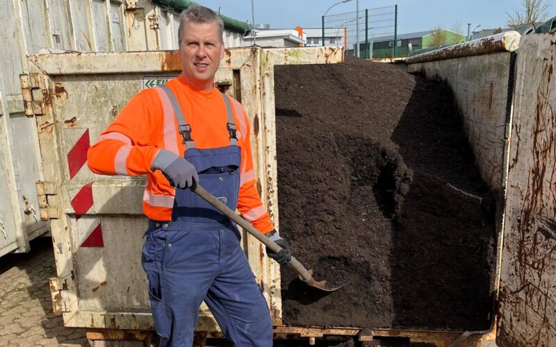 Bernd Westensee, ZVO Mitarbeiter, vor mit Kompost gefüllten Container stehend
