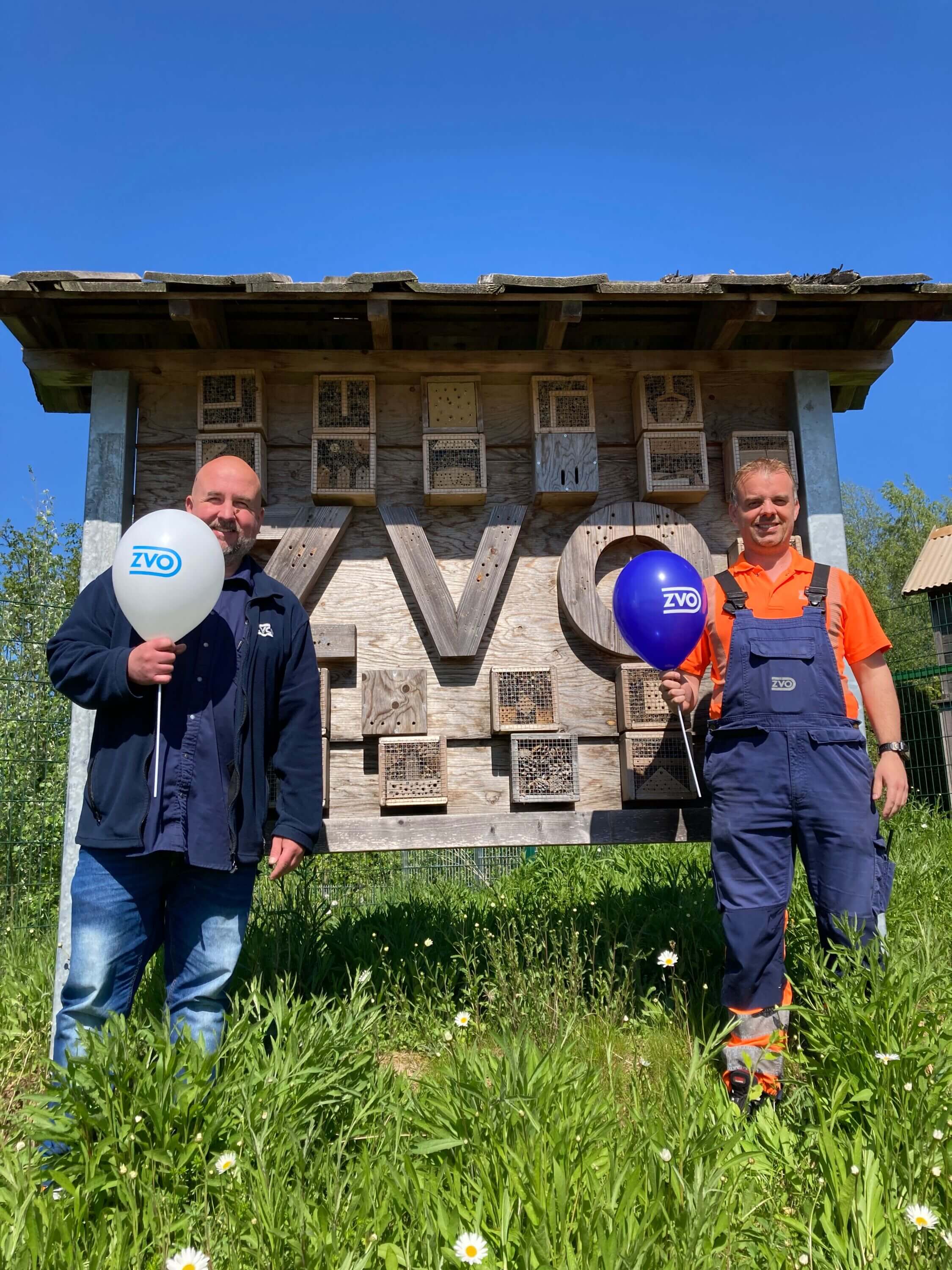 Mike-Andreas Dühning, Mitarbeiter und Sven Thode, Vorarbeiter Recyclinghof, vor einem Insektenhotel stehend, mit ZVO Luftballons in der Hand
